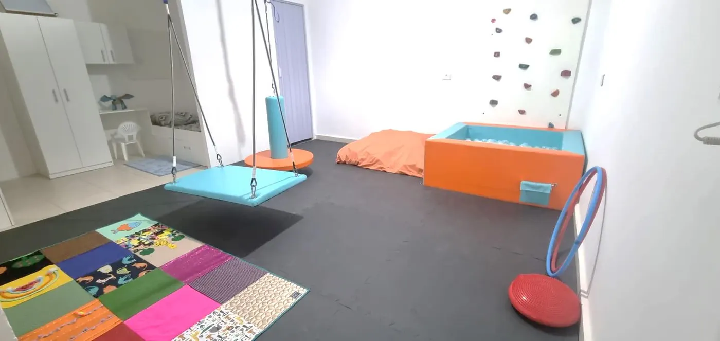 Sala de integração sensorial com balanço, piscina de bolinhas e parede de escalada