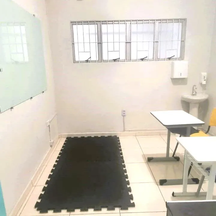 Sala de atendimento com tatame, mesa e lousa