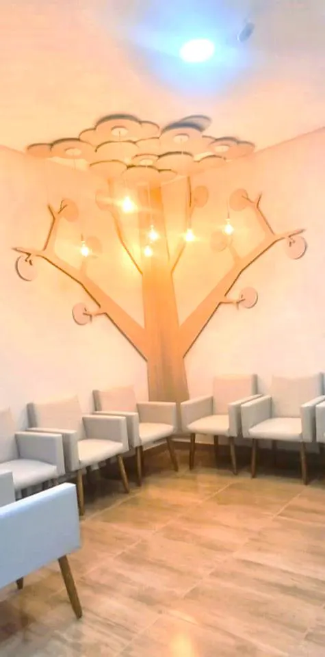 Sala de espera com painel de árvore e poltronas